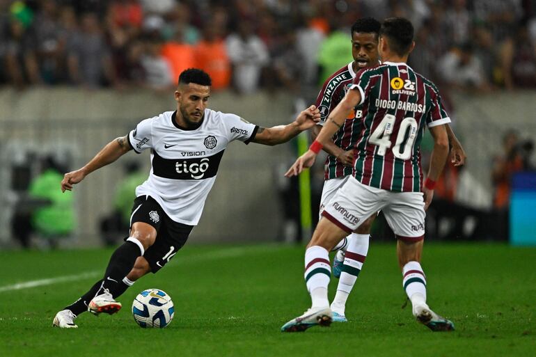 Fernando Cardozo (i), jugador de Olimpia, domina el balón frente a dos jugadores de Fluminense en el partido de ida de los cuartos de final de la Copa Libertadores 2023 en el estadio Maracaná, en Río de Janeiro, Brasil. 