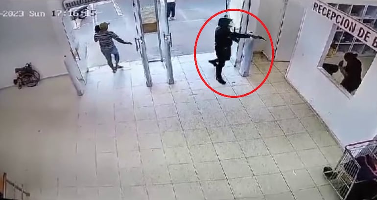 Captura de circuito cerrado en donde uno de los cuatro delincuentes que robaron un supermercado en Itauguá, apunta con un arma a una funcionaria.