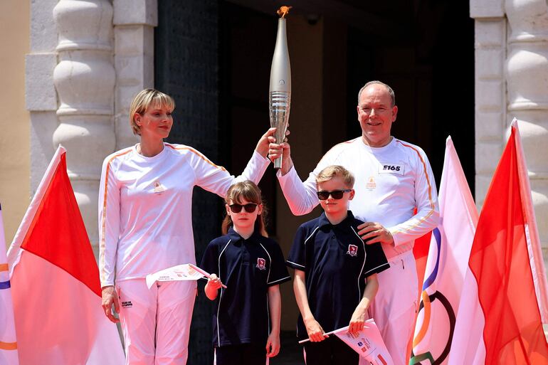 Alberto II de Mónaco y Charlene de Mónaco  sostienen la antorcha de la Llama Olímpica junto a la Princesa Gabriella y el Príncipe Jacques durante una ceremonia de relevo en Mónaco (Valery HACHE / AFP)