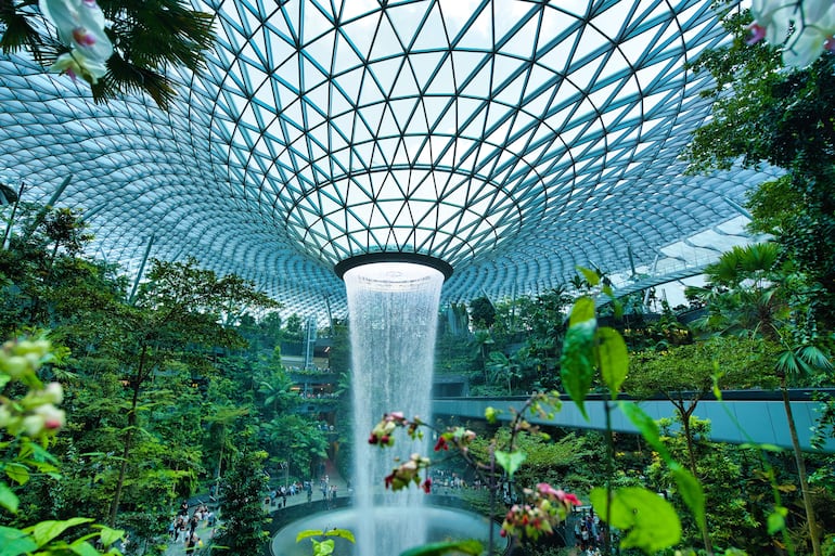 Vista en paralaje de la cascada interior de la cúpula del vórtice de lluvia en la selva tropical Jewel Changi, aeropuerto de Singapur.