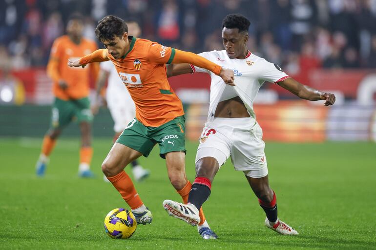 SEVILLA, 11/01/2025.- El centrocampista belga del Sevilla Albert-Mboyo (d) lucha con el portugués Andre Almeida, del Valencia, durante el partido de la jornada 19 de LaLiga que Sevilla FC y Valencia CF disputan este sábado en el Ramón Sánchez-Pizjuán, en Sevilla. EFE/Julio Muñoz
