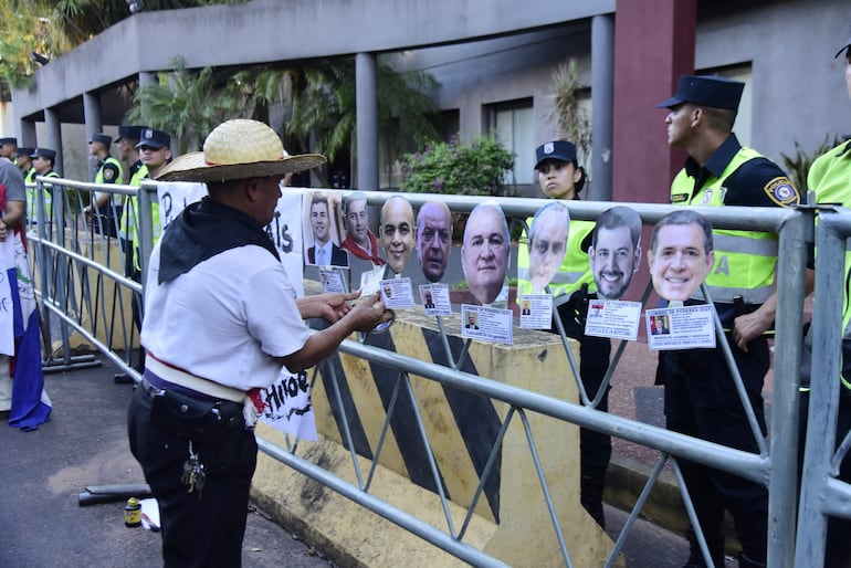 Un manifestante instala una galería de supuestos participantes de la “Cumbre de Mafiosos”, donde se incluyó a Horacio Cartes, jefe de ANR.