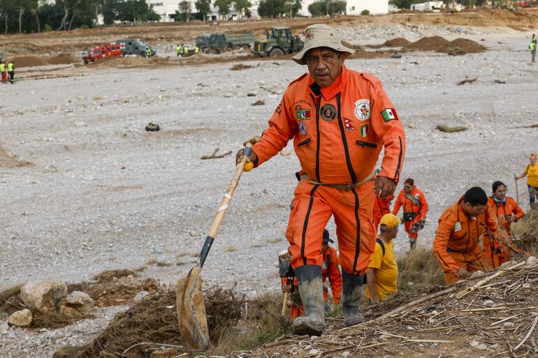 Un grupo de rescatistas mexicanos, de la Brigada Internacional de Rescate Topos Azteca, durante las tareas de búsqueda y rescate en la rambla del Poyo, una de las principales vías que recorrió el agua durante la riada, este jueves en Valencia. 