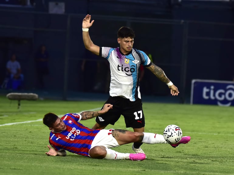 Juan Manuel Iturbe (en el suelo), jugador de Cerro Porteño, lucha por el balón con Matías Espinoza, futbolista de Libertad, en un partido del torneo Apertura 2024 del fútbol paraguayo en el estadio Defensores del Chaco, en Asunción.