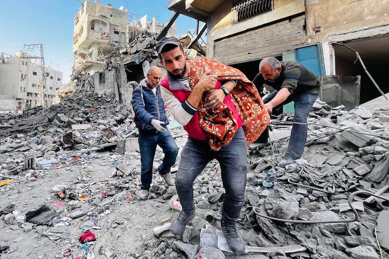 Tres hombres rescatan un cadáver de entre los escombros de un edificio destruido por un bombardeo israelí, el martes en Beit Lahia, en el norte de la Franja de Gaza.