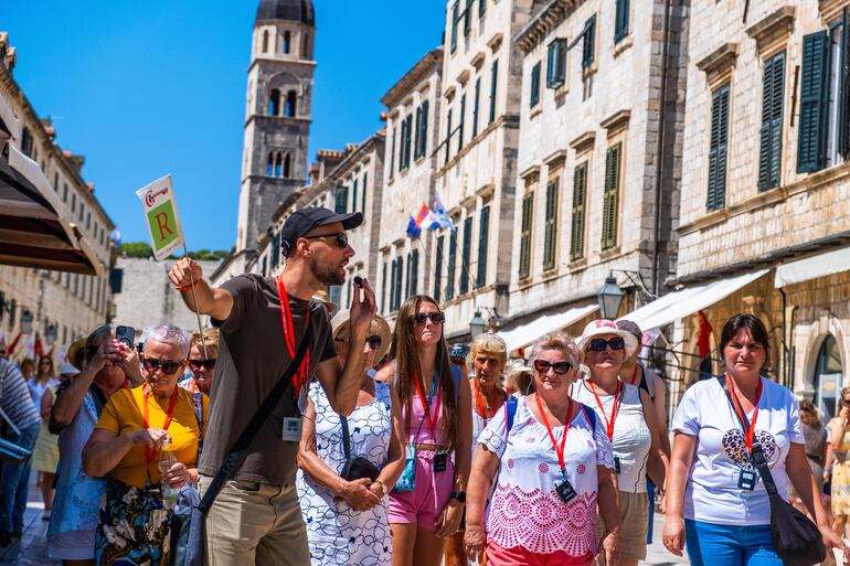 Un guía turístico lleva a un grupo de turistas a lo largo de Stradun, la calle principal del casco antiguo de Dubrovnik, Croacia.