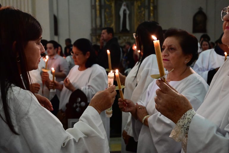 Los fieles iluminan la oscuridad con la luz proveniente del cirio pascual