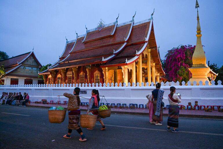 Estas mujeres pasan junto a una pagoda al amanecer en Luang Prabang. 