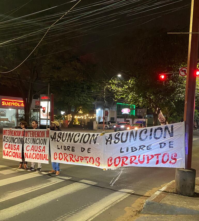 Cuando el semáforo está en rojo, ciudadanos extienden carteles que piden la intervención de la administración del intendente Óscar "Nenecho" Rodríguez (ANR - HC).