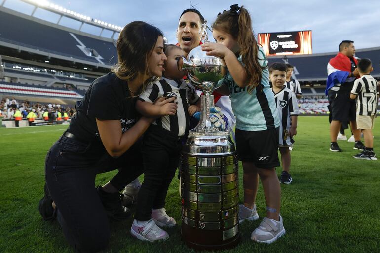 Roberto Junior Fernández, arquero de Botafogo, celebra con su familia y el trofeo de campeón la conquista de la Copa Libertadores 2024 después de superar a Atlético Mineiro en la final en el estadio Monumental, en Buenos Aires, Argentina.