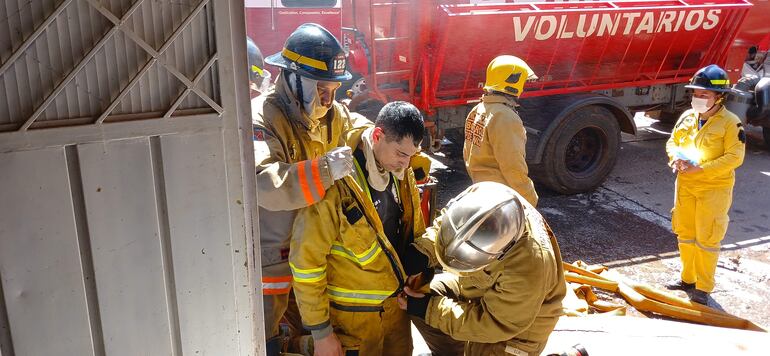 Un voluntario es asistido por sus compañeros tras salir del edificio en llamas. 