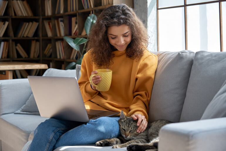 joven acariciando un gato y tomando café