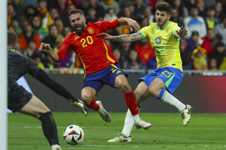 El defensa de la selección brasileña Lucas Lopes Beraldo (d) comete penalti sobre Dani Carvajal, de la selección española, durante el partido amistoso que las selecciones nacionales de fútbol de España y Brasil han disputado hoy martes en el estadio Santiago Bernabéu, en Madrid.