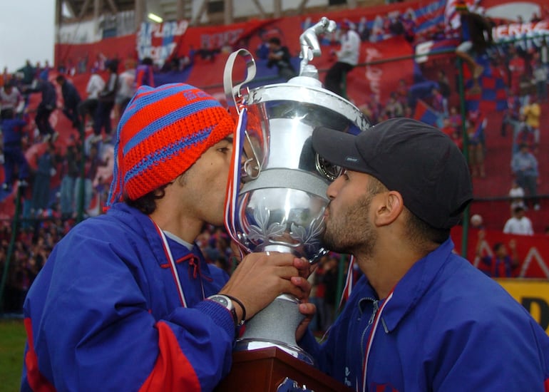 Santiago Salcedo y Ernesto Cristaldo, jugadores de Cerro Porteño, besan el trofeo de campeón del torneo Apertura 2005.