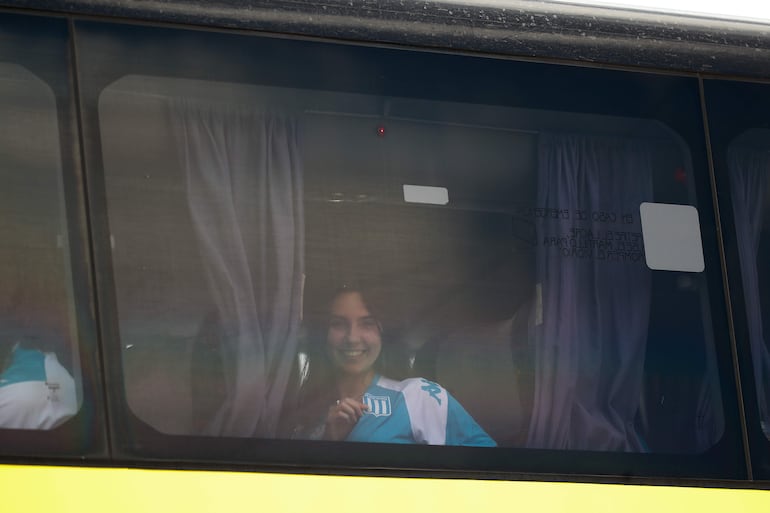 Una hinchas de Racing muestra el escudo de Racing desde un autobús.