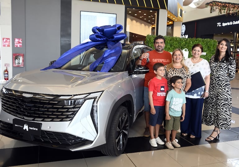 Darío Penayo y su familia reciben el premio por parte de Sara Lezcano, gerente del Shopping, y Josefina Pedersen, la escribana.