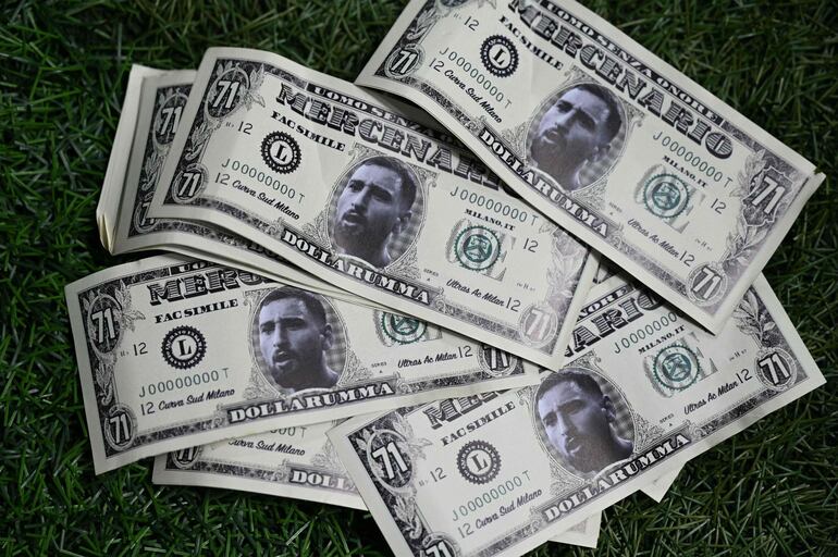 Billetes de dólares falsos que muestran un retrato del portero italiano del Paris Saint-Germain #99 Gianluigi Donnarumma yacía en el césped después de ser arrojado por seguidores del PSG durante el partido de fútbol del grupo F de la primera ronda de la Liga de Campeones de la UEFA entre el AC Milan y el Paris Saint-Germain en San Siro. estadio de Milán el 7 de noviembre de 2023. (Foto de GABRIEL BOUYS / AFP)