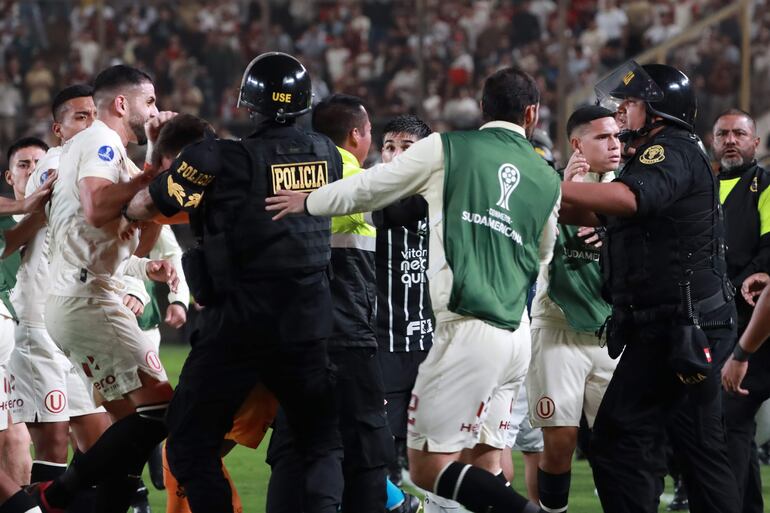 Los jugadores de Universitario se enfrentan a la policía en un partido de la Copa Sudamericana contra Corinthians en el estadio Monumental, en Lima, Perú.