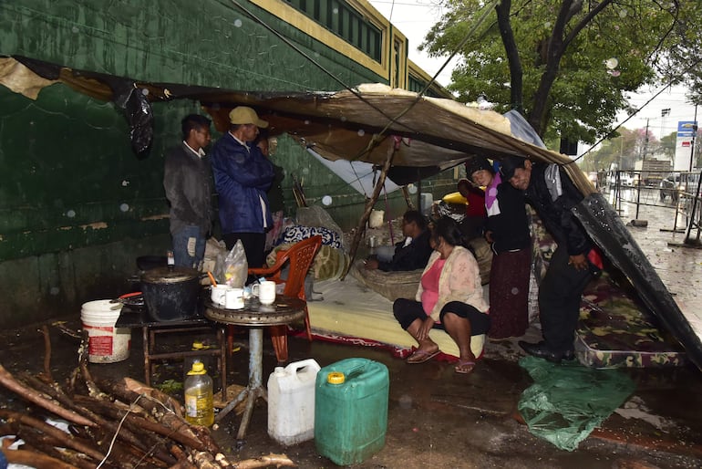 Una familia de indígenas en precarias carpas soporta la intensa lluvia en la vereda, frente al Indi, sobre la avenida Artigas.