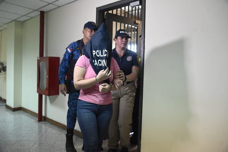 La oficial ayudante Gabriela Vasso Mosqueira aparece escoltada por una agente de la Dirección de Hechos Punibles Económicos y Financieros.