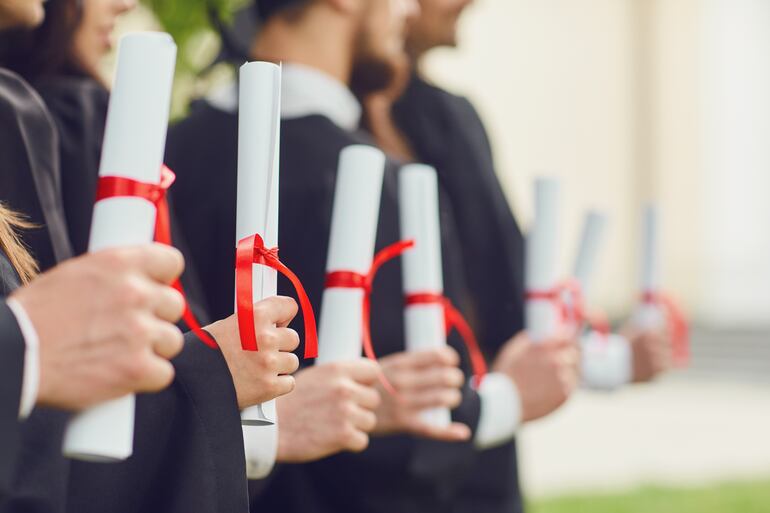 Graduados con sus diplomas enroscados en las manos.