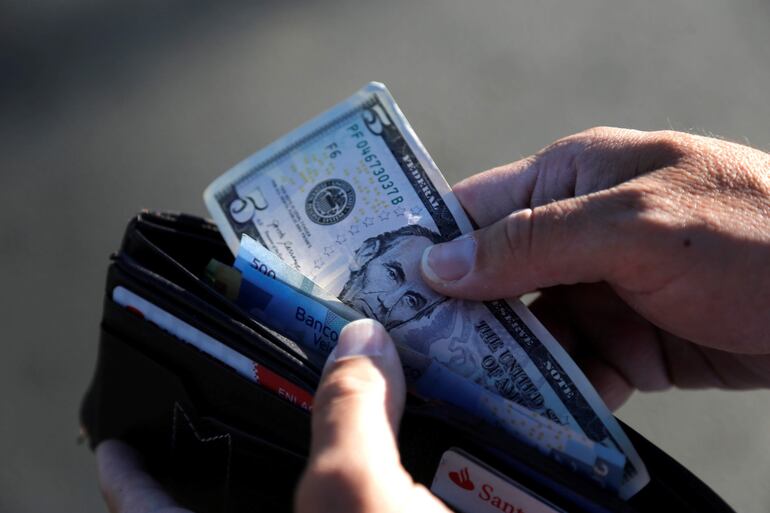 Una persona guarda en su cartera un billete de cinco dólares.