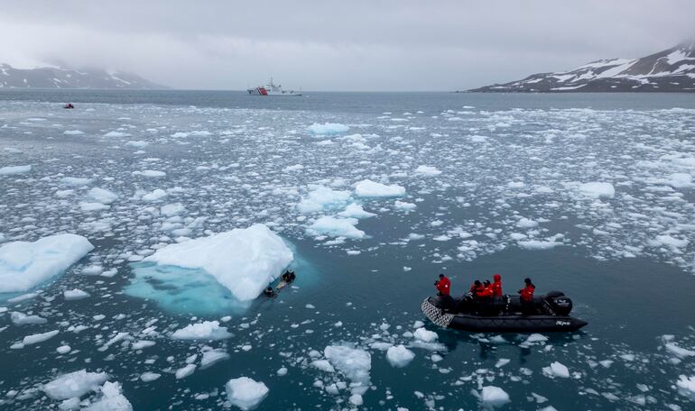 La bióloga de la Cornell University de Nueva York sumerge un hidrófono cubierto de titanio y atado a una boya, en medio del imponente océano coronado por témpanos de hielo, en el archipiélago de las Islas Shetland del Sur.