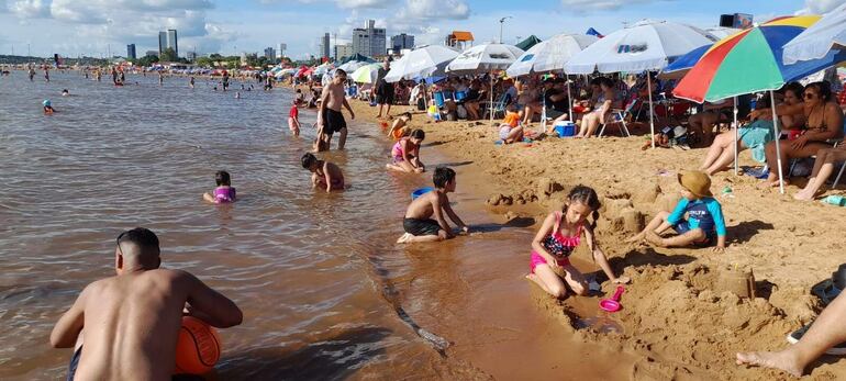  Numerosos niños disfrutan jugando en la arena y de las cristalinas aguas del río Paraná. 