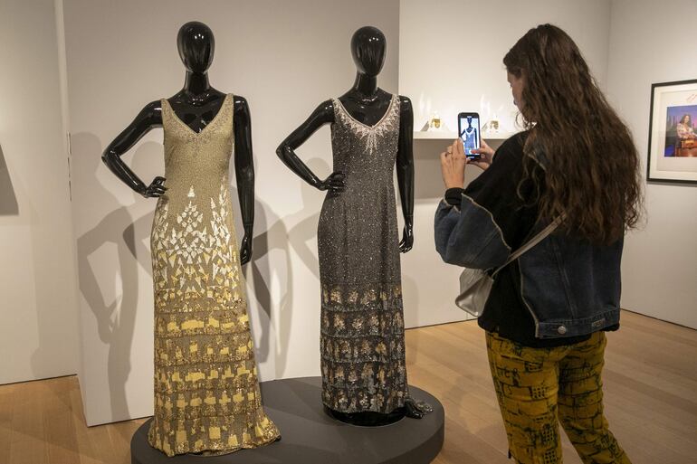 Una mujer fotografía vestidos de Donna Summer exhibidos en Christie's .