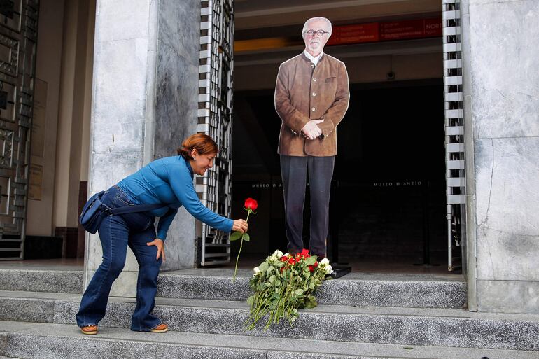 Una mujer deposita una rosa roja a los pies de una imagen del artista colombiano Fernando Botero, en la entrada del Museo de Antioquia en Medellín, Colombia, el 15 de septiembre de 2023, el día de su fallecimiento