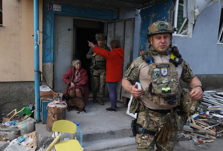 Los agentes de la fuerza policial especial "Ángel Blanco" Hennadiy Yudin, de 47 años (derecha) y Dmytro Solovyi, de 23 (izq.), hablan con mujeres durante la evacuación de residentes locales.