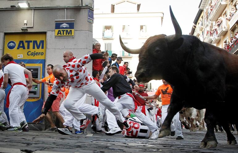 Los toros de la ganadería de La Palmosilla, de Tarifa (Cádiz), a su paso por la curva de la calle de Mercaderes, durante el séptimo encierro de los Sanfermines 2019