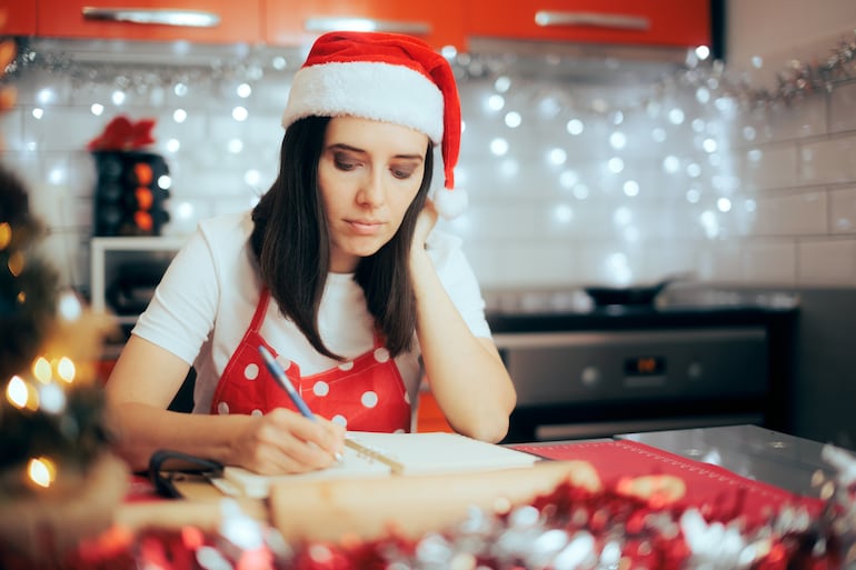 Mujer hace una lista de ingredientes para Navidad.