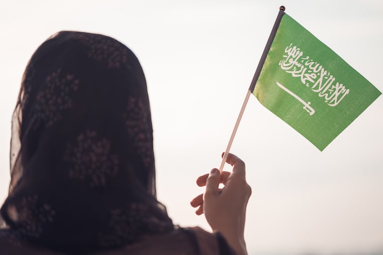 Mujer musulmana bandera de Arabia Saudita al atardecer.