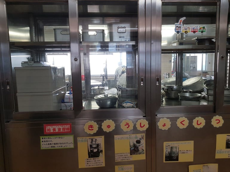 Cocina completamente equipada y personal con uniforme adecuado para preparar el almuerzo escolar en una escuela pública de Tokio, Japón.