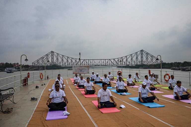 Oficiales aduaneros participan de una sesión de yoga a bordo de un barco en el río Hoogly, en Calcuta. 