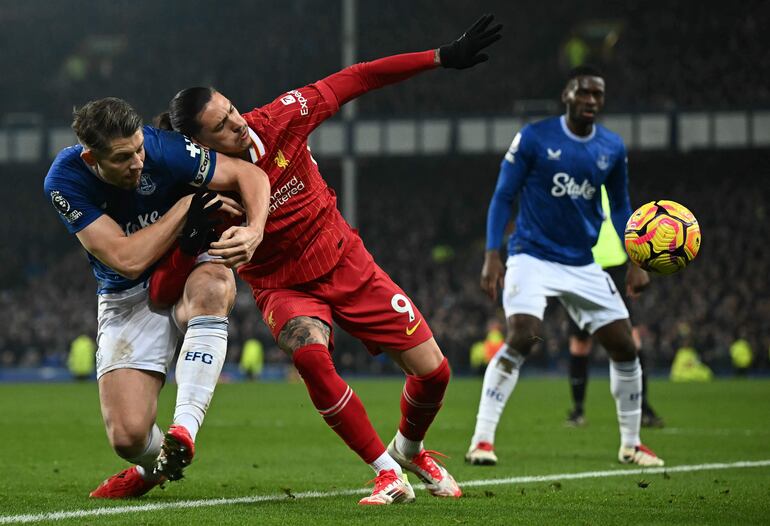 Everton's English defender #06 James Tarkowski (L) vies with Liverpool's Uruguayan striker #09 Darwin Nunez during the English Premier League football match between Everton and Liverpool at Goodison Park in Liverpool, north west England on February 12, 2025. (Photo by Paul ELLIS / AFP) / RESTRICTED TO EDITORIAL USE. No use with unauthorized audio, video, data, fixture lists, club/league logos or 'live' services. Online in-match use limited to 120 images. An additional 40 images may be used in extra time. No video emulation. Social media in-match use limited to 120 images. An additional 40 images may be used in extra time. No use in betting publications, games or single club/league/player publications. / 