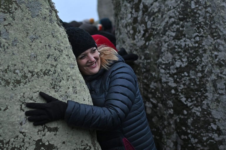 Una asistente interactúa con una piedra mientras las personas se reúnen para celebrar el festival pagano del "Solsticio de Invierno" en Stonehenge, en Wiltshire, en el sur de Inglaterra, el 21 de diciembre de 2024.