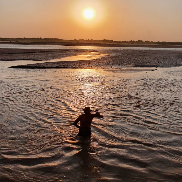 Un hombre busca aplacar el intenso y sofocante calor que se abatió sobre el Chaco paraguayo sumergiéndose en el río Pilcomayo.