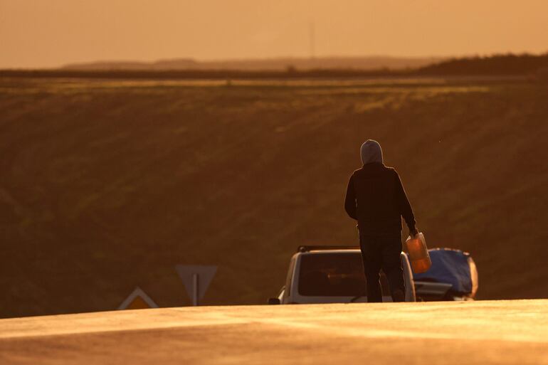 Un refugiado con un contenedor de gasolina camina hacia un vehículo luego de cruzar la frontera de Nagorno Karabaj hacia Armenia, este jueves.