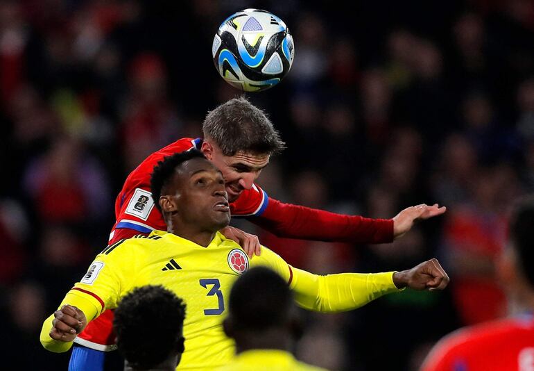 Jhon Lucumi (3), futbolista de la selección de Colombia, pelea por el balón junto a Diego Valdés, jugador de Chile, en un partido de las Eliminatorias Sudamericanas al Mundial 2026 en el estadio Monumental, en Santiago, Chile.