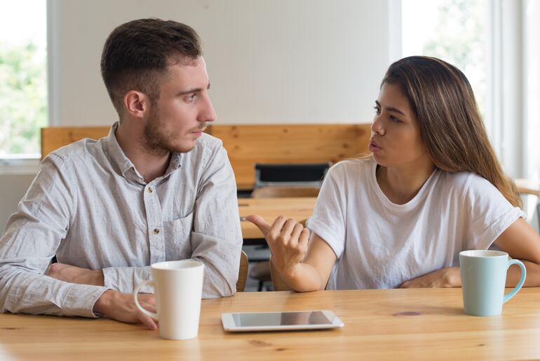 Jóvenes serios conversando y tomando té en una cafetería. Jóvenes sentados en una mesa.