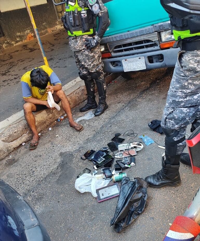 hombre de remera azul y amarilla tapándose la cara. Frente a él policías. Foto: Facebook