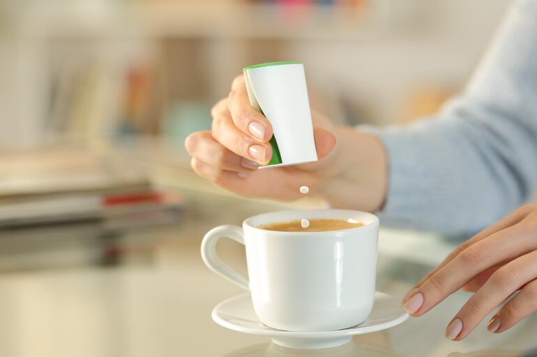 Una mujer endulza su café con sacarina.