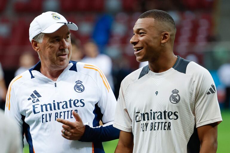 Kylian Mbappé (d), jugador del Real Madrid, recibe instrucciones de su entrenador italiano Carlo Ancelotti en el entrenamiento del plantel en Varsovia en la víspera del partido de la Supercopa de Europa contra Atalanta. 