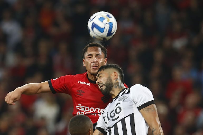 Duelo aéreo entre el joven atacante brasileño Vitor Roque (18 años) y el argentino Alexander Barboza (28), durante el duelo de anoche en el estadio mundialista Arena da Baixada, en Curitiba. EFE