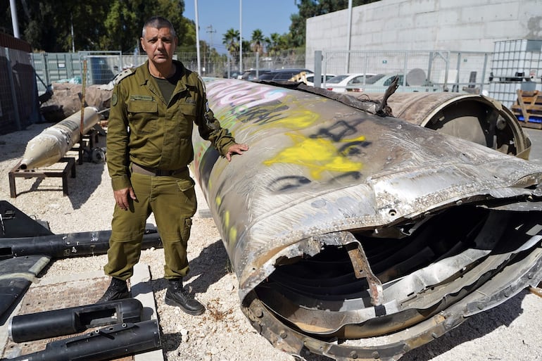 El coronel Olivier Rafowicz, portavoz de las Fuerzas de Defensa de Israel, posa junto a uno de los misiles balísticos que Irán lanzó en su ataque del pasado 1 de octubre y que fue derribado por el sistema defensivo Cúpula de Hierro, este miércoles en la base militar de Julis (Israel), donde el ejército israelí también ha mostrado a la prensa munición de Hezbolá requisada en sus operaciones militares en Líbano.