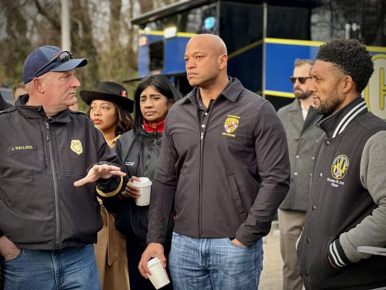 El gobernador de Maryland, Wes Moore (c), y el alcalde de Baltimore, Brandon M. Scott (d), atienden a la información del Jefe de bomberos de la ciudad de Baltimore, James Wallace (i), después de que el puente Francis Scott Key se derrumbase tras recibir el impacto el carguero "Dali" contra uno de sus pilares, este martes en Baltimore, Estados Unidos. 