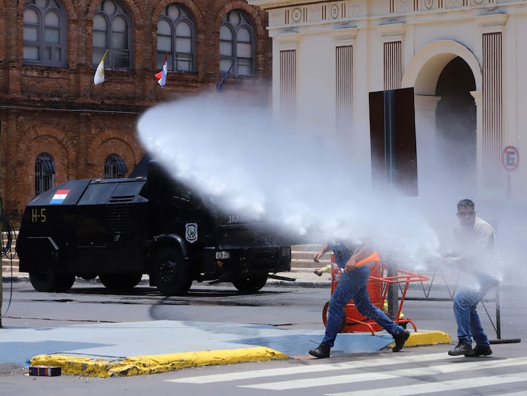 Frente a la Catedral Metropolitana de Asunción un carro hidrante dispara un potente chorro de agua contra los manifestantes que protestaban por la sanción en el Senado de la ley que crea la Superintendencia de Jubilaciones.