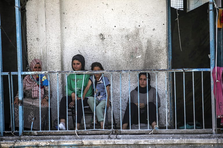 Palestinos desplazados internos miran desde el balcón de un edificio escolar de la UNRWA dañado tras un ataque aéreo israelí en el campamento de refugiados de Al Nusairat, en la Franja de Gaza central, el 6 de junio de 2024.